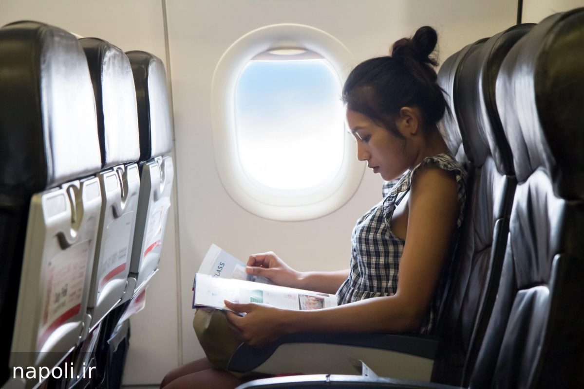 دختری در هواپیما در حال مطالعه مجله و رعایت روتین مراقبت از پوست